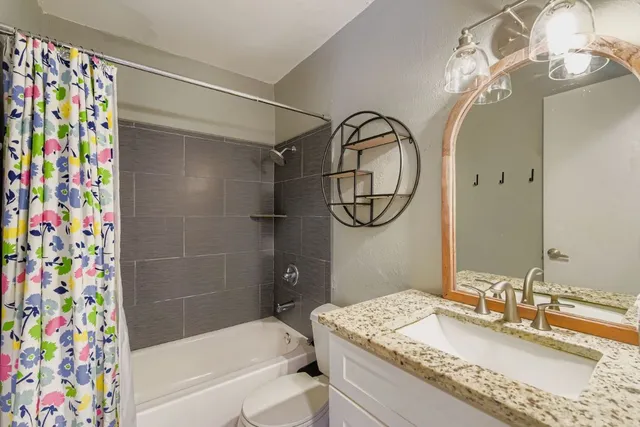 a bathroom with a granite countertop sink a mirror a vanity and a shower