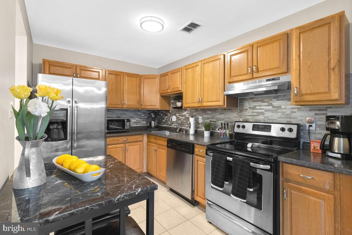 a kitchen with granite countertop stainless steel appliances a stove a sink a counter space and cabinets