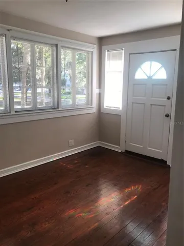 a view of an empty room with wooden floor and a window