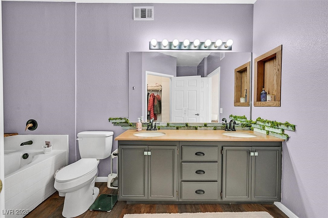 10550 West Alexander Road, Unit 2065 Las Vegas, NV 89129 - Photo 16 of 27 Full bathroom with double vanity, a bath, a textured wall, dark wood-type flooring, and a spacious closet
