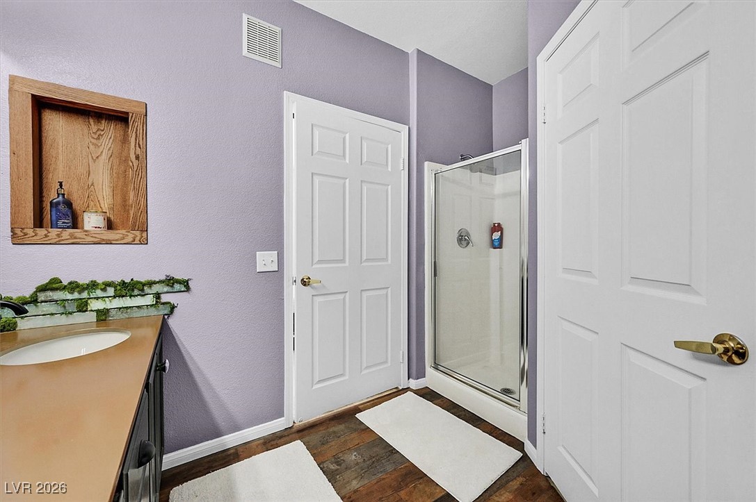 10550 West Alexander Road, Unit 2065 Las Vegas, NV 89129 - Photo 17 of 27 Full bathroom featuring vanity, a stall shower, dark wood-style floors, and a textured wall