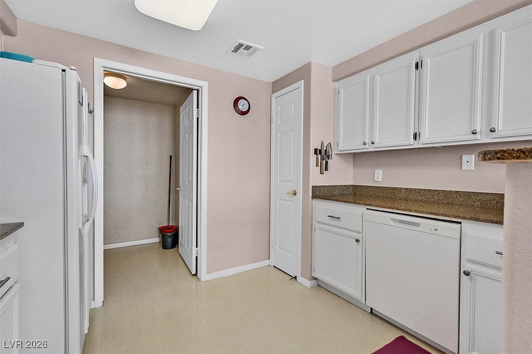 10550 West Alexander Road, Unit 2065 Las Vegas, NV 89129 - Photo 8 of 27 Kitchen featuring light flooring, white appliances, white cabinetry, and dark stone counters