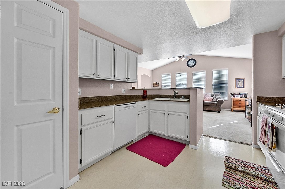 10550 West Alexander Road, Unit 2065 Las Vegas, NV 89129 - Photo 9 of 27 Kitchen with vaulted ceiling, white cabinets, white appliances, ceiling fan, and a textured ceiling