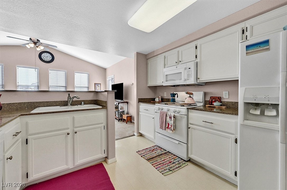 10550 West Alexander Road, Unit 2065 Las Vegas, NV 89129 - Photo 10 of 27 Kitchen with white appliances, white cabinets, a ceiling fan, light floors, and lofted ceiling