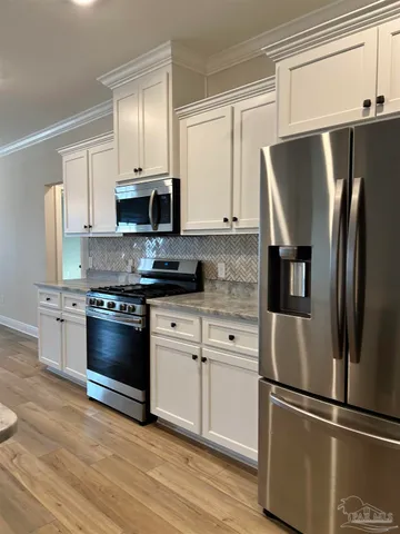 a living room with stainless steel appliances kitchen island granite countertop a refrigerator a sink a dining table and chairs with wooden floor