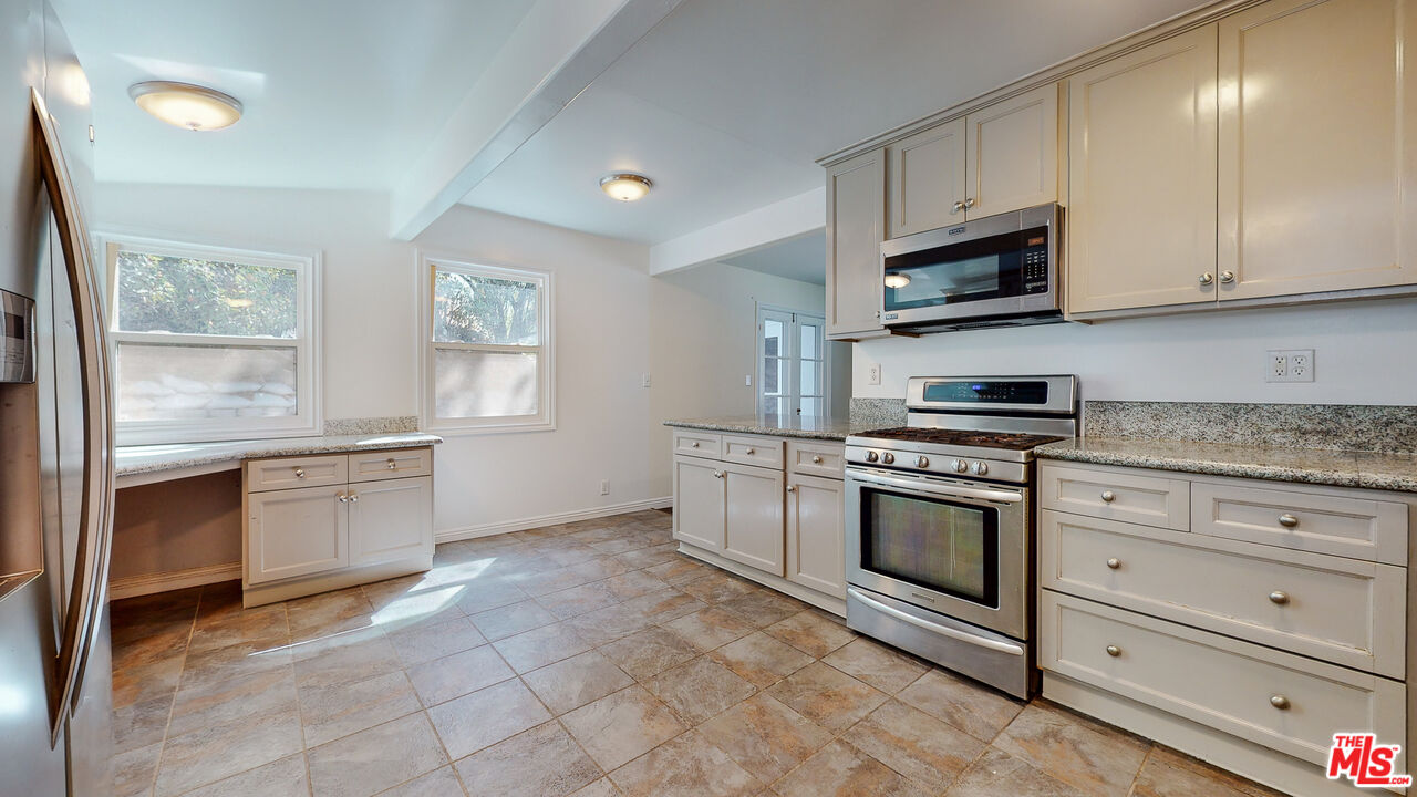 7865 Denivelle Road Sunland, CA 91040 - Photo 21 of 54 a kitchen with stainless steel appliances granite countertop white cabinets a sink a stove a microwave and a window