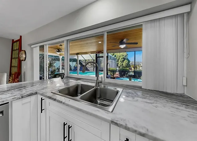 a kitchen with stainless steel appliances granite countertop a sink a stove a refrigerator cabinets and a dining table