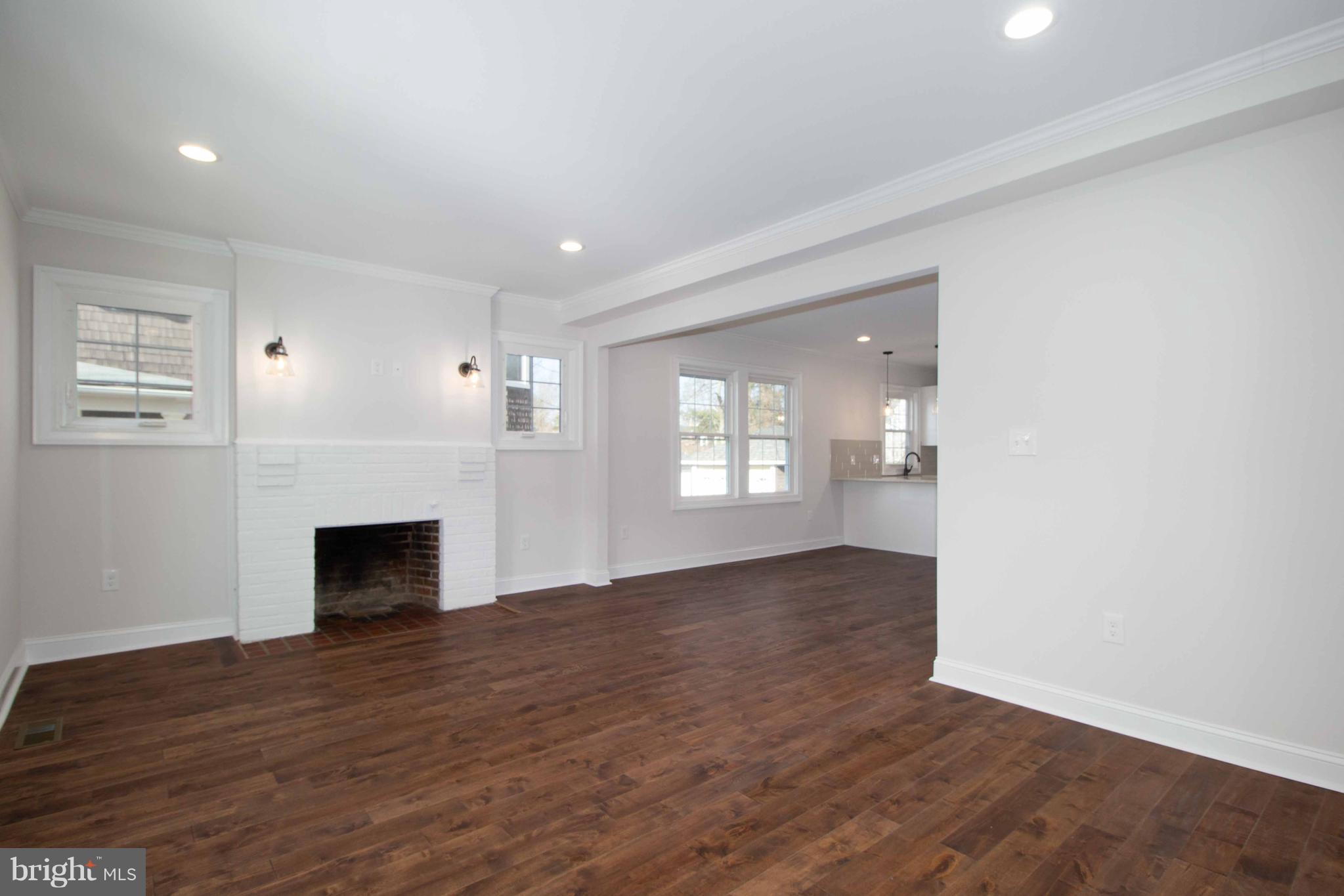 701 Brookwood Road Baltimore, MD 21229 - Photo 8 of 57 an empty room with wooden floor fireplace and windows