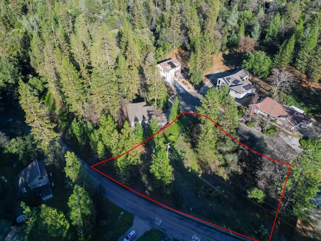 an aerial view of residential house with outdoor space and trees all around