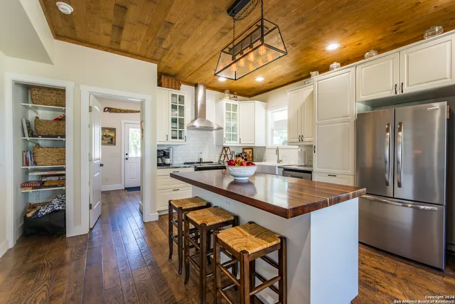 a kitchen with stainless steel appliances granite countertop a refrigerator a sink dishwasher a stove and white countertops with wooden floor