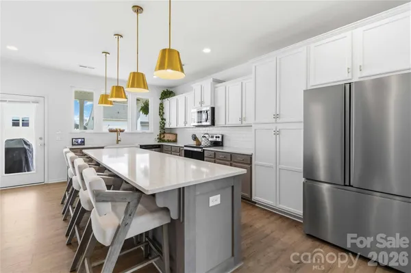 a kitchen with stainless steel appliances granite countertop a refrigerator a sink a stove a dining table and chairs