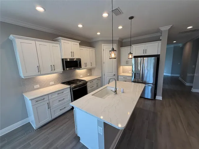 a kitchen with a refrigerator a sink dishwasher a stove and a oven with wooden floor