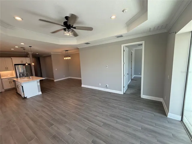 an empty room with wooden floor and a ceiling fan