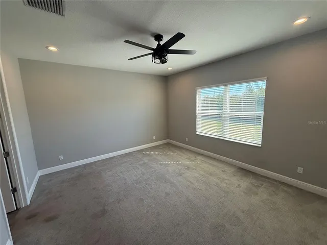 an empty room with a ceiling fan and windows