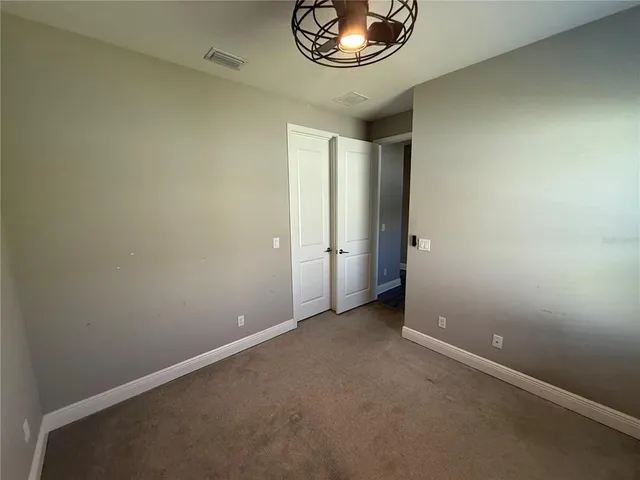 an empty room with a chandelier fan and glass door