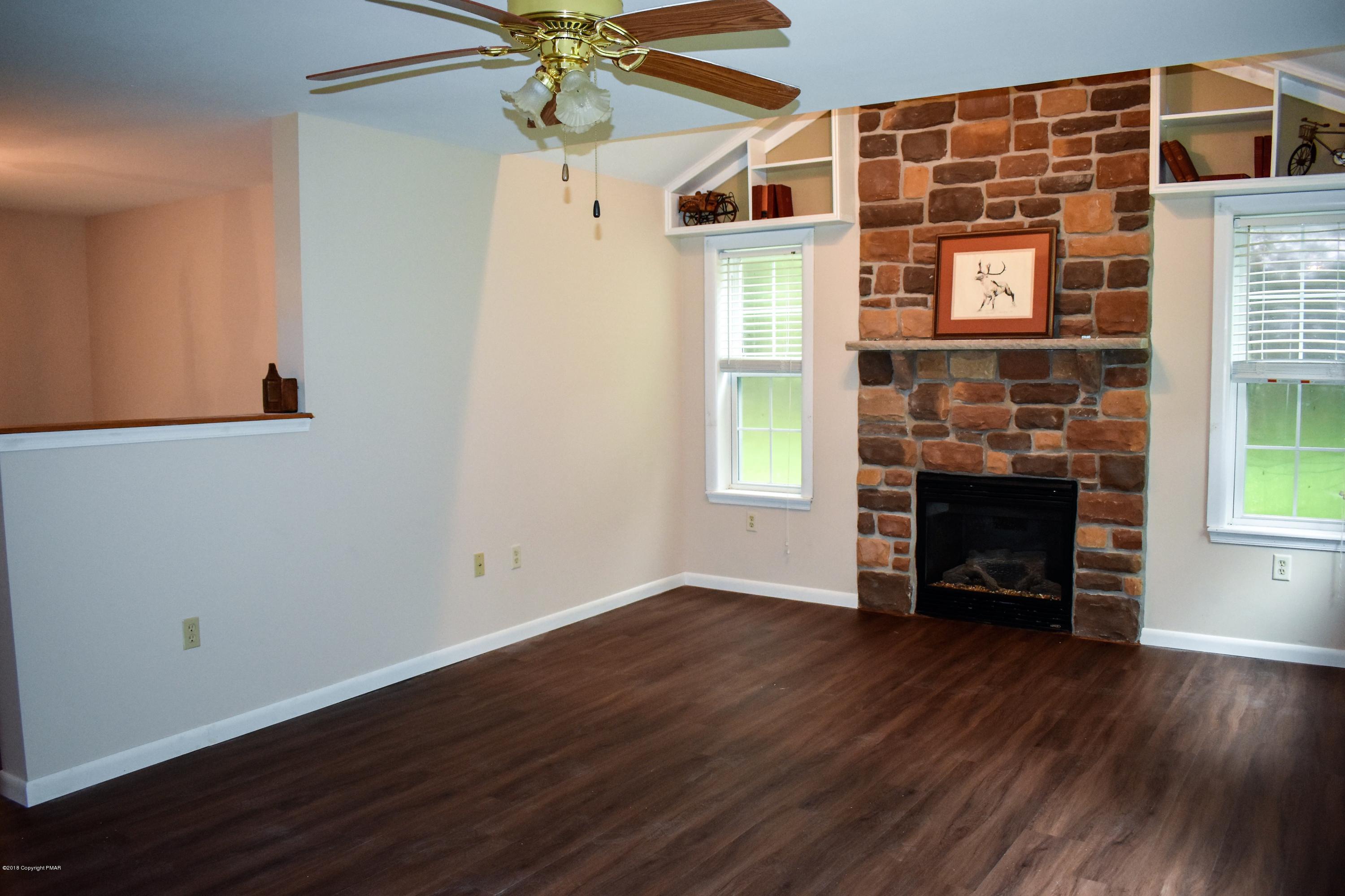 33 Sassafras Road Albrightsville, PA 18210 - Photo 4 of 36 an empty room with wooden floor a fireplace and windows