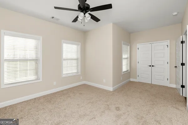 an empty room with ceiling fan and window