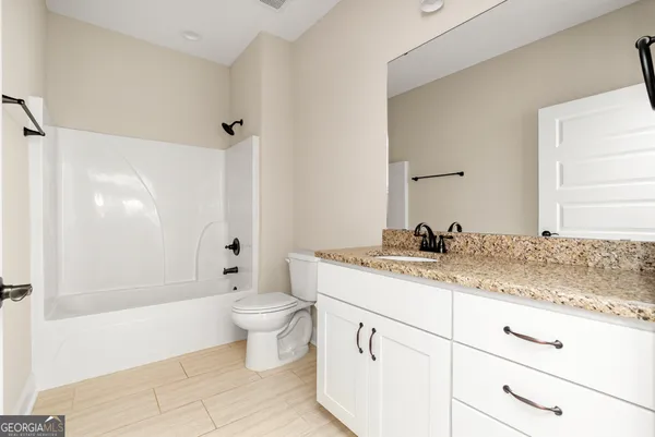 a view of an empty room with closet and a bathroom