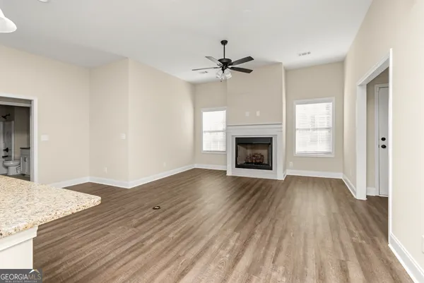 an empty room with wooden floor fireplace and windows
