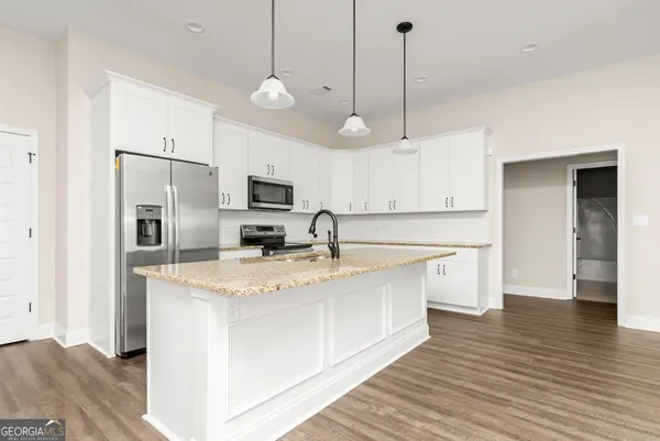 a large kitchen with stainless steel appliances granite countertop a sink a stove and a wooden floors