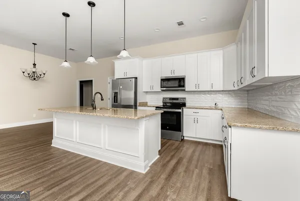 a kitchen with kitchen island a white counter top space cabinets and stainless steel appliances