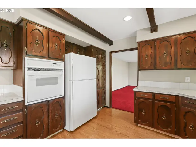 a kitchen with stainless steel appliances granite countertop a refrigerator a stove and a sink with wooden cabinets