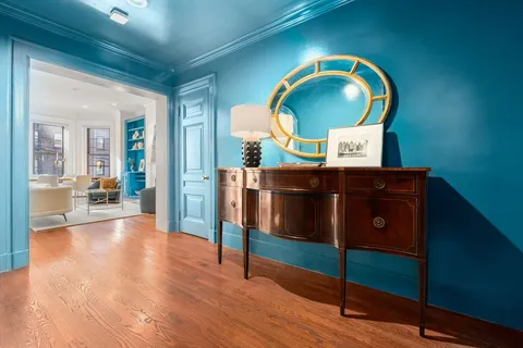an entryway with wooden floor and mirror on a table