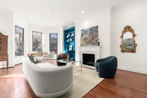 a living room with furniture a fireplace and a floor to ceiling window