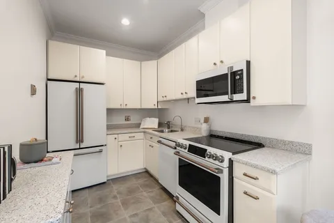 a kitchen with stainless steel appliances granite countertop white cabinets a microwave a sink and a refrigerator