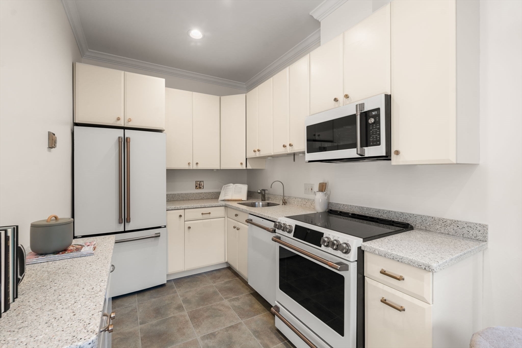 457 Beacon Street, Unit 5 Boston, MA 02115 - Photo 9 of 22 a kitchen with stainless steel appliances granite countertop white cabinets a microwave a sink and a refrigerator