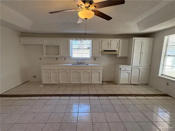 a kitchen with white cabinets appliances and window