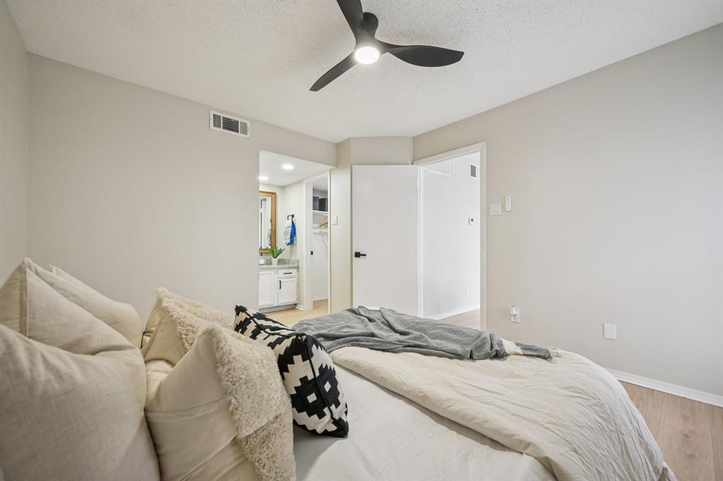18333 Roehampton Drive, Unit 128 Dallas, TX 75252 - Photo 13 of 40 a bedroom with a bed and a chandelier