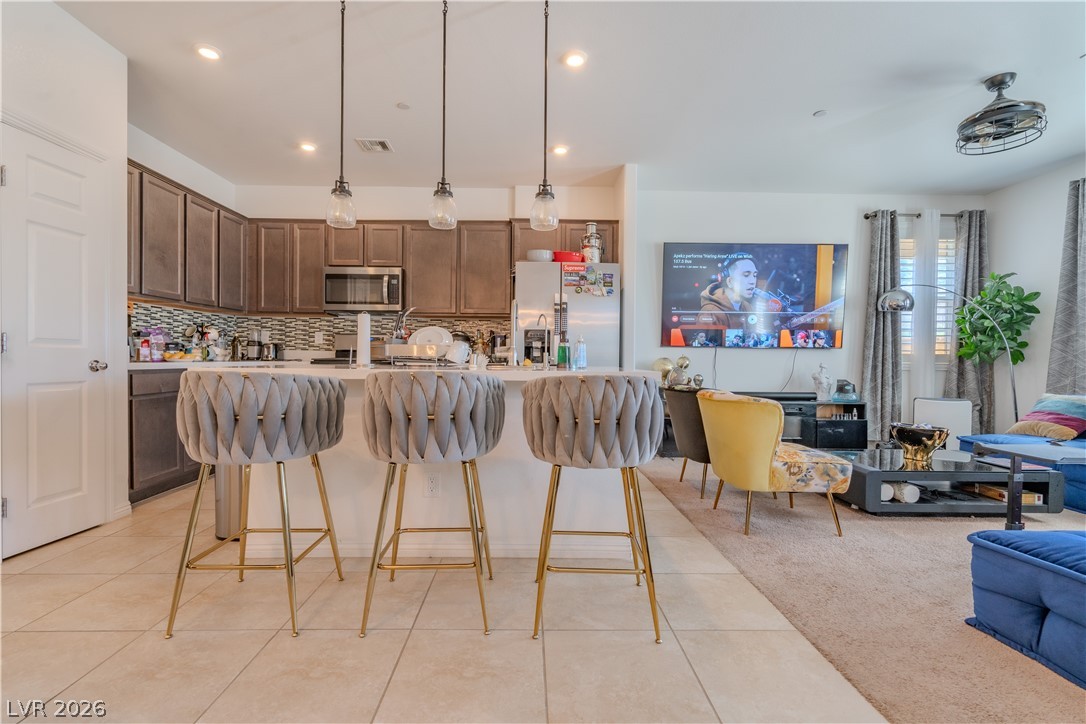 1239 Raritan Place Henderson, NV 89002 - Photo 1 of 26 Kitchen with a breakfast bar area, hanging light fixtures, a center island with sink, backsplash, and stainless steel appliances