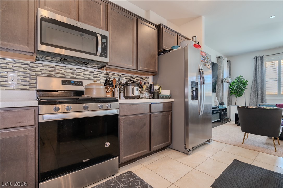 1239 Raritan Place Henderson, NV 89002 - Photo 5 of 26 Kitchen with stainless steel appliances, dark wood finish cabinetry, light countertops, and light tile patterned floors