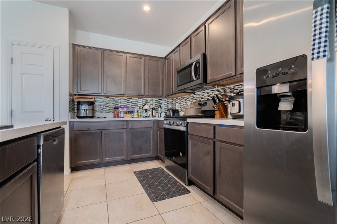 1239 Raritan Place Henderson, NV 89002 - Photo 6 of 26 Kitchen featuring stainless steel appliances, dark wood finish cabinets, light countertops, and light tile patterned flooring