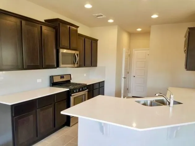 a kitchen with stainless steel appliances a sink dishwasher a refrigerator and a stove with wooden cabinets