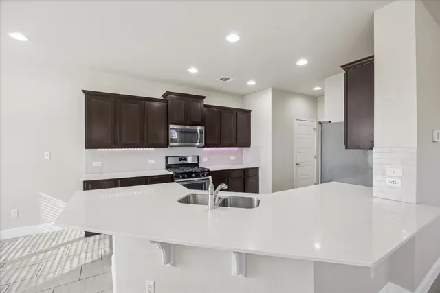 a kitchen with stainless steel appliances kitchen island sink refrigerator and cabinets