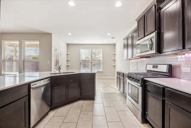 a large kitchen with stainless steel appliances granite countertop a stove sink and cabinets