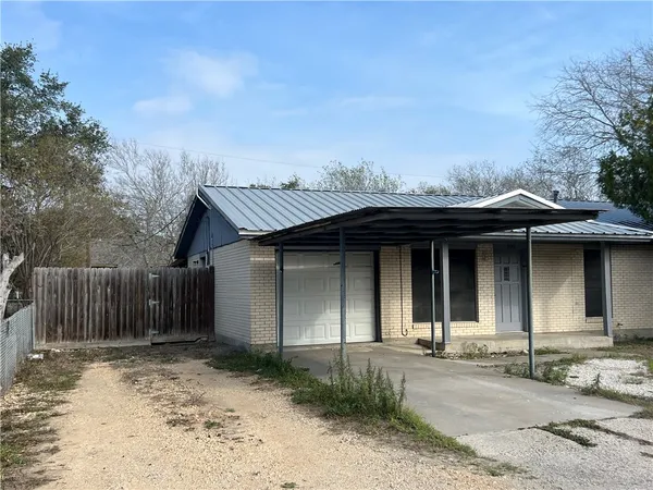 a view of a house with small yard plants and wooden fence