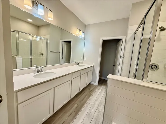 a bathroom with a double vanity sink and mirror with shower