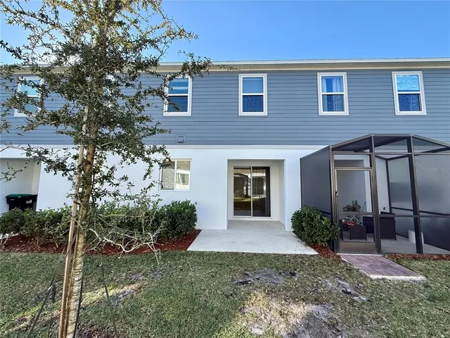 a view of a brick house with a yard potted plants and a table