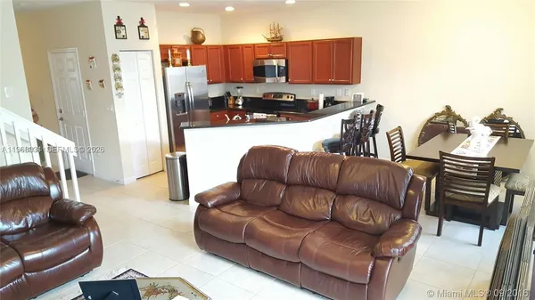 a living room with furniture a flat screen tv and a refrigerator