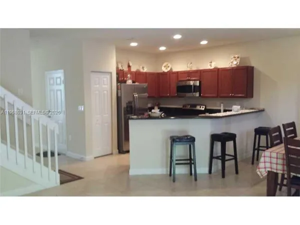 a kitchen with stainless steel appliances kitchen island granite countertop a refrigerator and cabinets