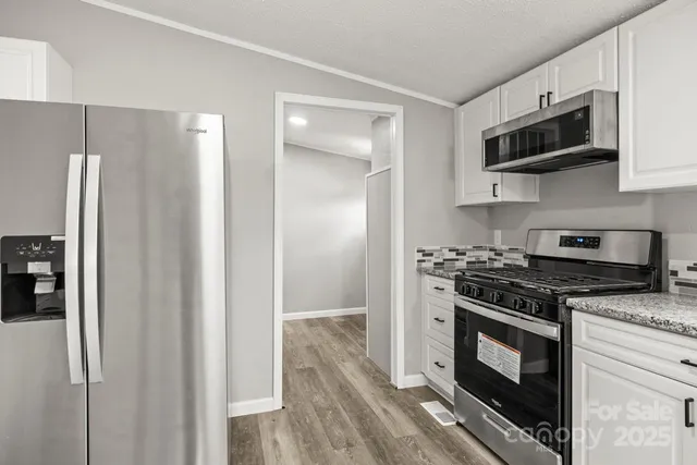 a kitchen with stainless steel appliances granite countertop a stove a refrigerator and a microwave