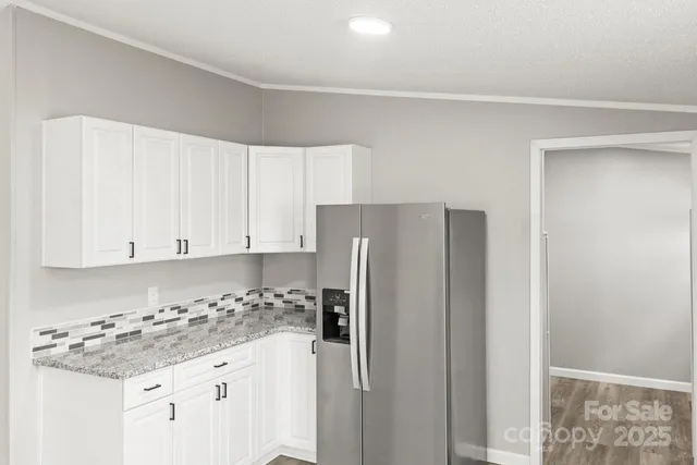 a kitchen with stainless steel appliances granite countertop a refrigerator and white cabinets