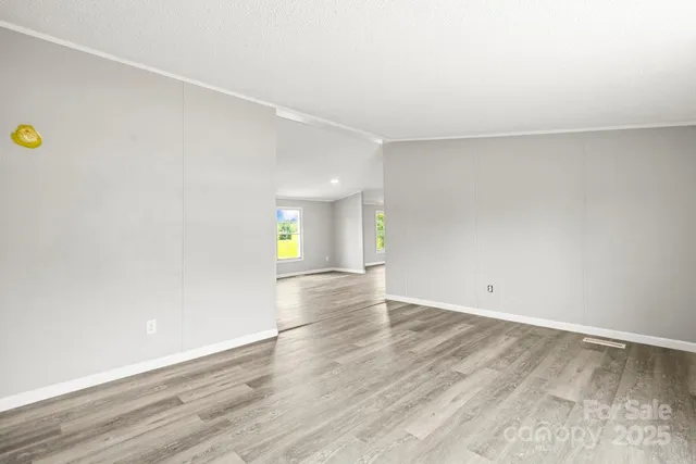 a view of an empty room with wooden floor and window