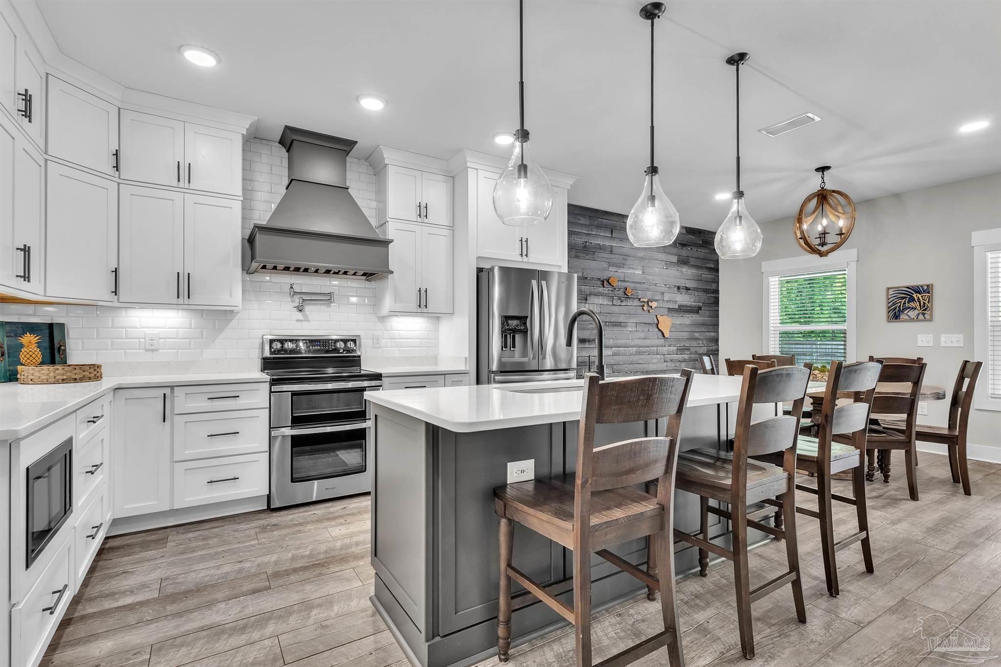 107 Countri Lane Cantonment, FL 32533 - Photo 7 of 35 a kitchen with stainless steel appliances a stove a table chairs and a chandelier