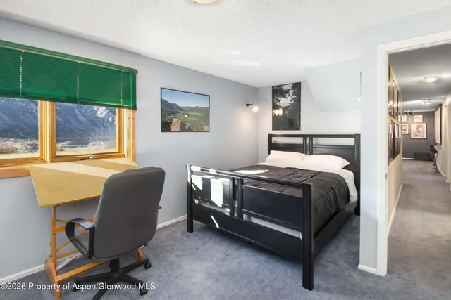 a bedroom with a bed chair and painting on the wall