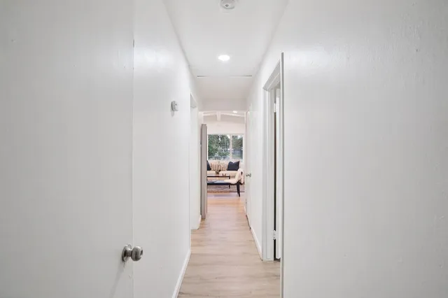 a view of a hallway with wooden floor and a bathroom