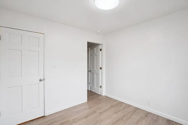 a view of an empty room with wooden floor and closet